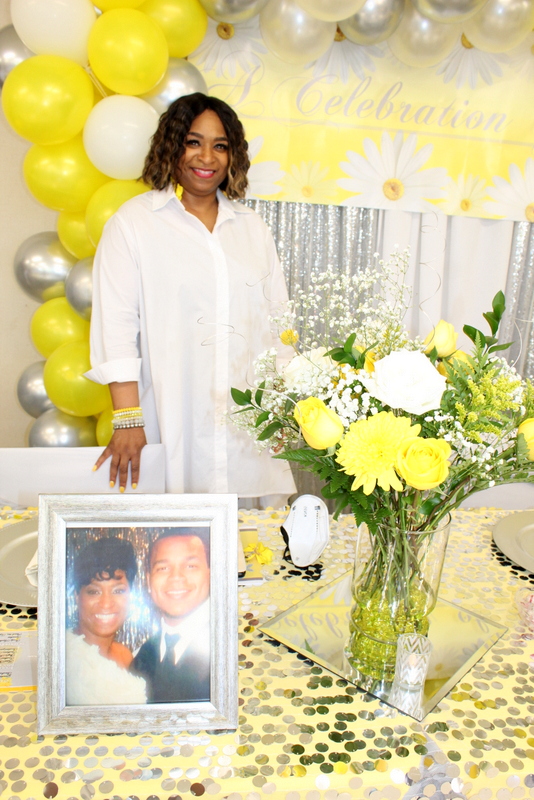 Angelica, founder of Comforting Hearts Foundation, standing beside a framed photograph of her son, Allen